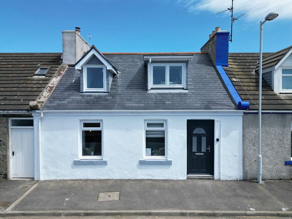 A white house with two front windows and a black door under a blue sky at Westview in Whithorn