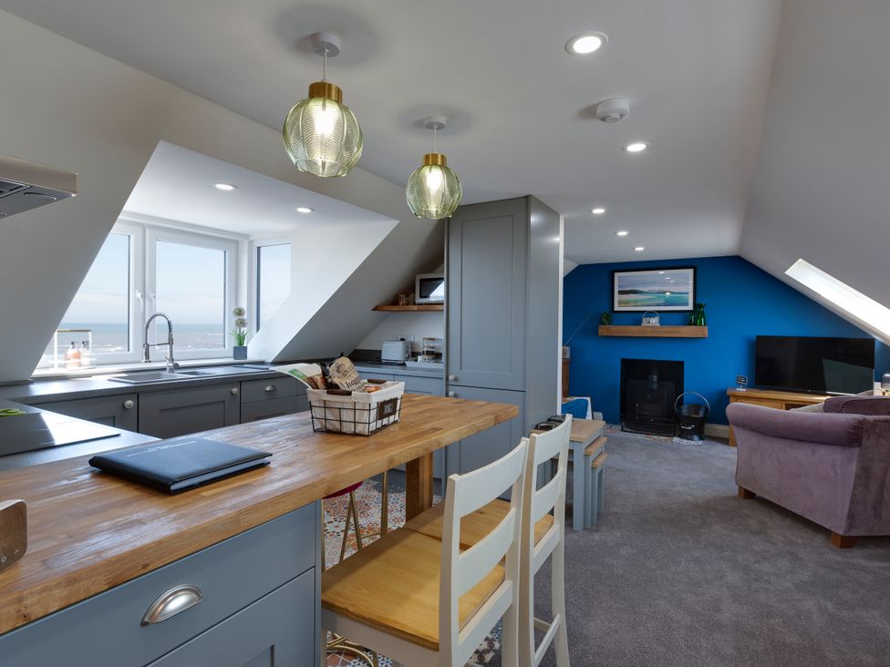 A kitchen and living area with wooden countertops a blue accent wall and a television at Westview in Whithorn