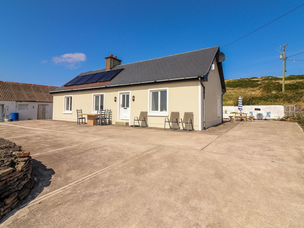 A house with outdoor chairs and tables on a concrete patio at Cottage View in Moveen East near Kilkee County Clare