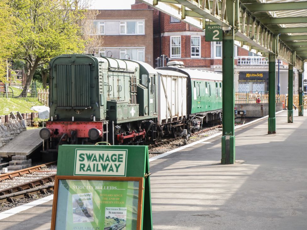 A green old train on tracks at a train station platform with a sign Swanage Railway and platform 2 visible at Swanage