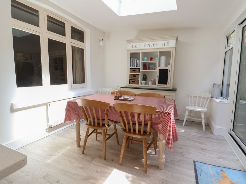 A dining area with a table covered by a red checkered cloth and wooden chairs next to a cabinet labeled cafe epices the at 5 Belmont Terrace in Beer