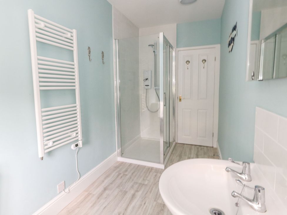 A bathroom with a sink a walk in shower a white heated towel rail and a door at Embassy Brewers Quay Harbour
