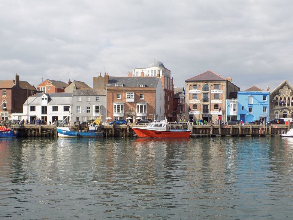 A waterfront view with boats docked by a row of commercial buildings and cafes at Embassy Brewers Quay Harbour