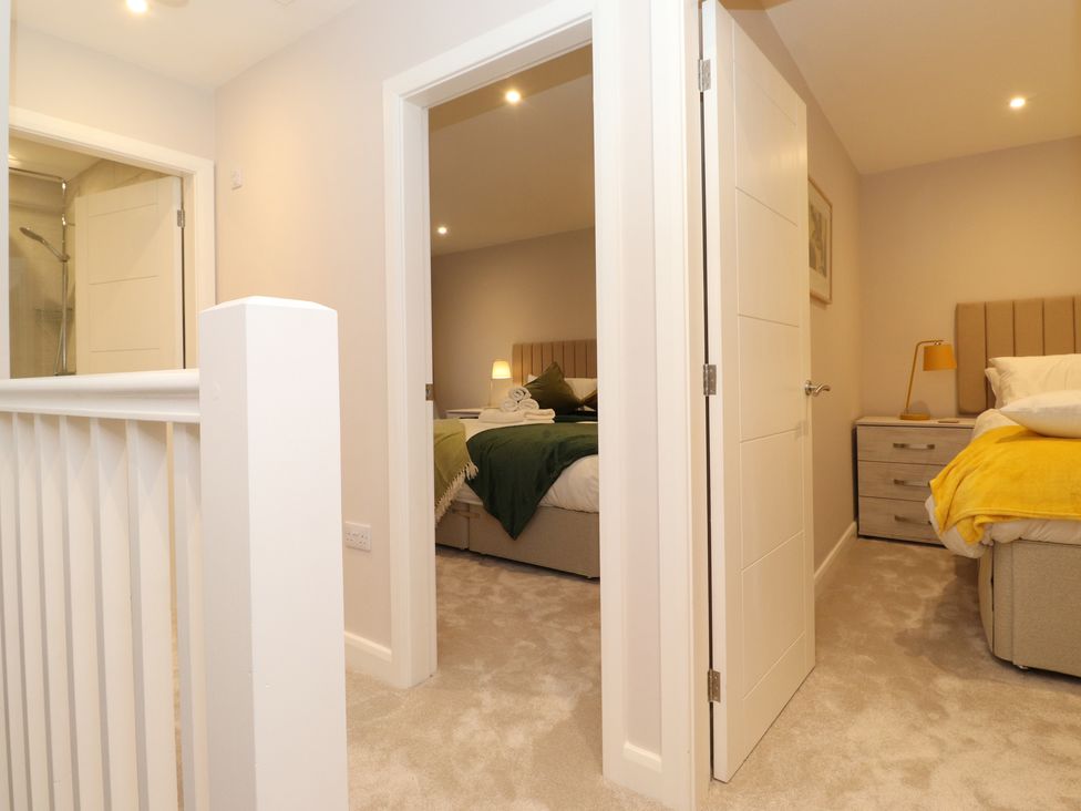 View of two bedrooms with beds and bedside tables from a hallway at Merry Bank in Ambleside