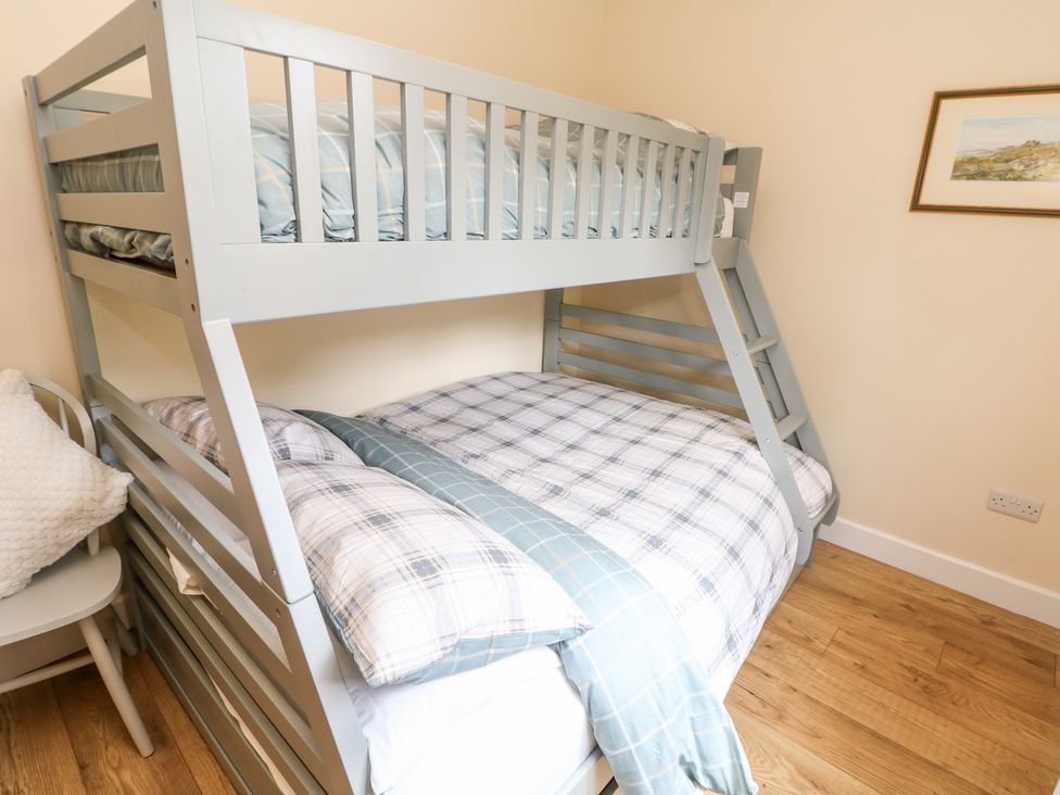 A bedroom with a grey bunk bed and a chair with a white cushion at Brookside in Hayfield