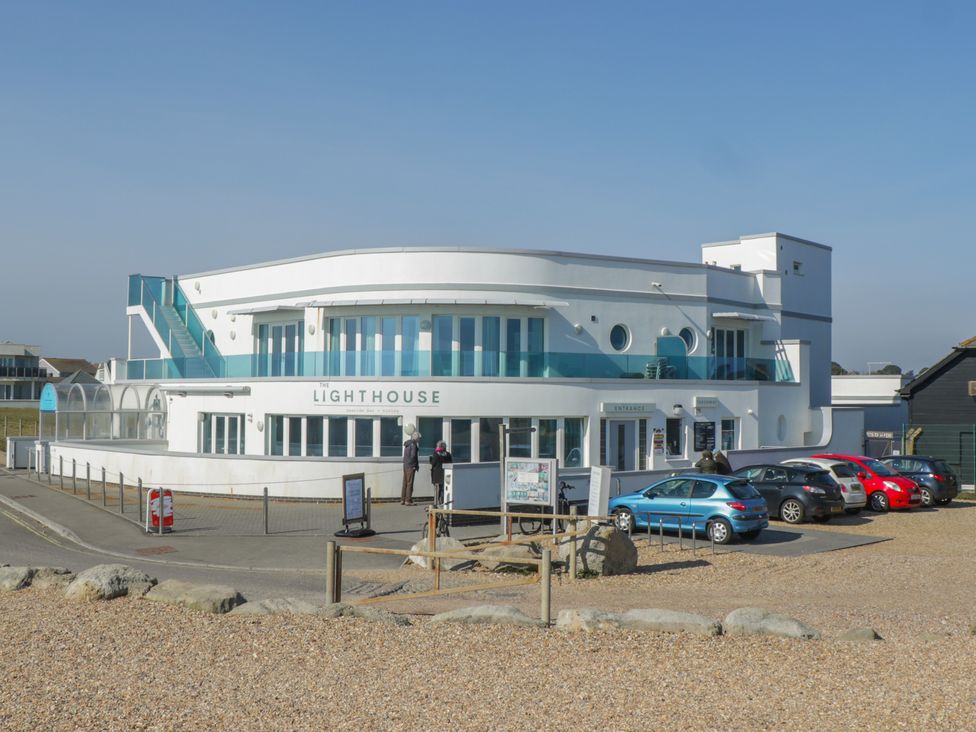 The exterior of a white two story building named The Lighthouse with a parking lot and cars in front at Swallow Lodge in Milford On Sea