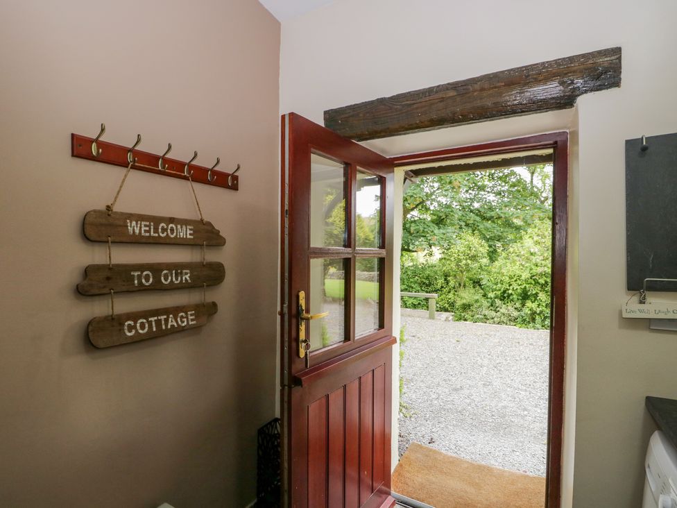 An open wooden door leading outside with a welcome sign hanging on a wall inside at Ewedale Farm in Pennington near Ulverston