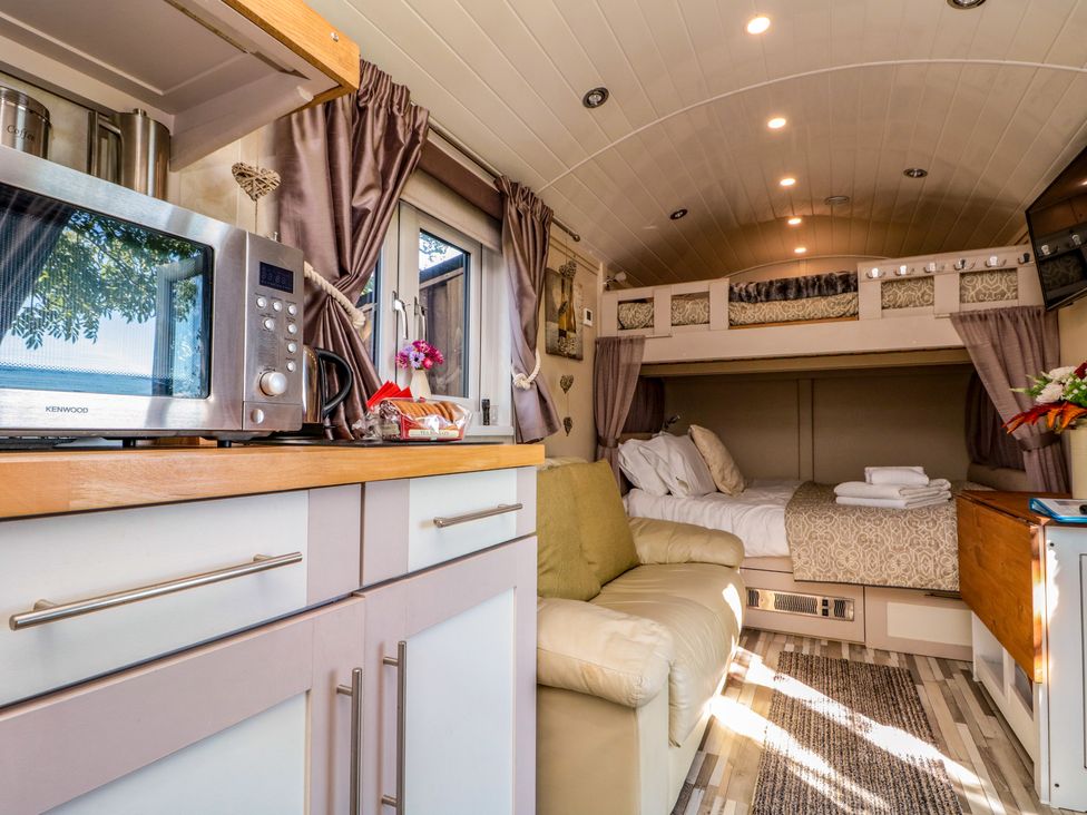 A small living space with a microwave on a counter a sofa and a bunk bed area at The Shepherd's Rest in Robin Hood's Bay
