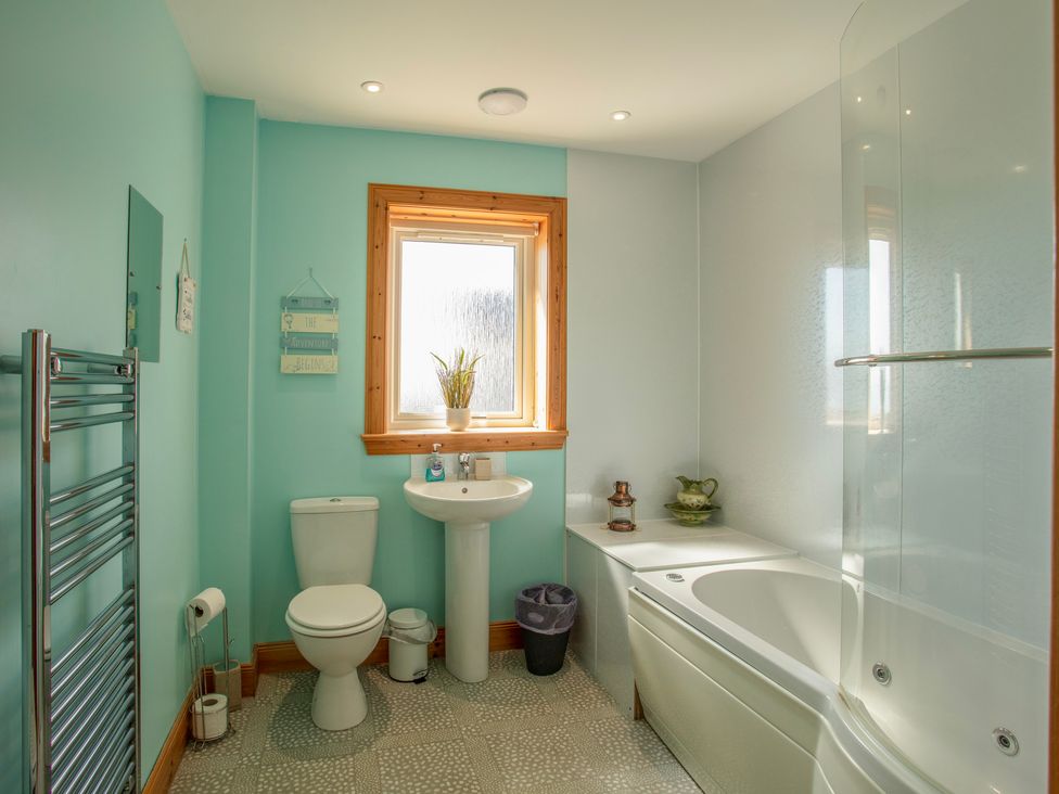 A bathroom with a toilet sink window bathtub and towel rack at Rockpool in Glendale Isle of South Uist