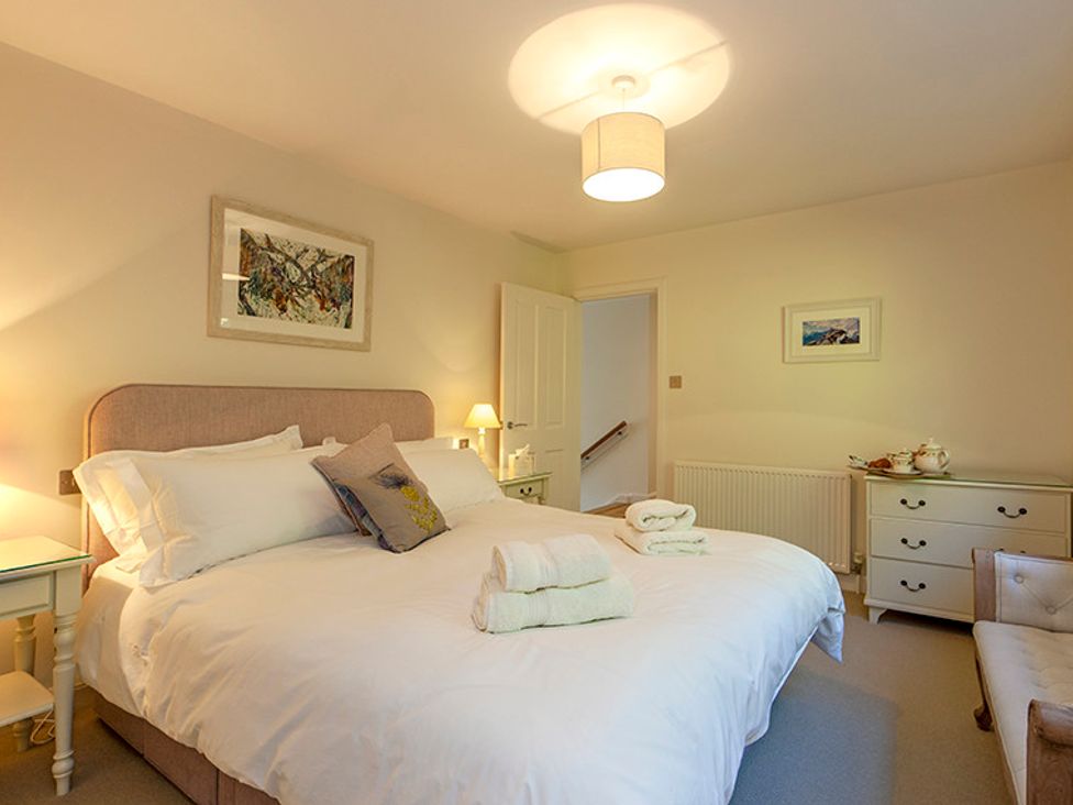 A bedroom with a large bed towels on the bed and a dresser in Mullach Ruadh Glenfinnan near Corpach