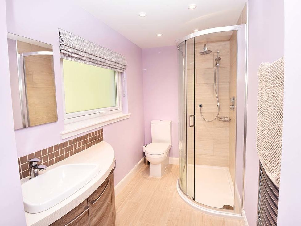 A bathroom with a sink cabinet mirror toilet curved glass shower and towel on radiator at Mullach Ruadh in Glenfinnan near Corpach