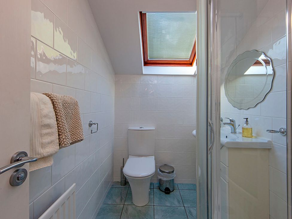A bathroom with a toilet sink mirror towels and a skylight window at Mullach Ruadh in Glenfinnan near Corpach