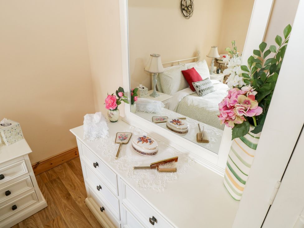 A bedroom with a white dresser mirror and floral decorations at Cartron Cottage in Ballintubber County Mayo