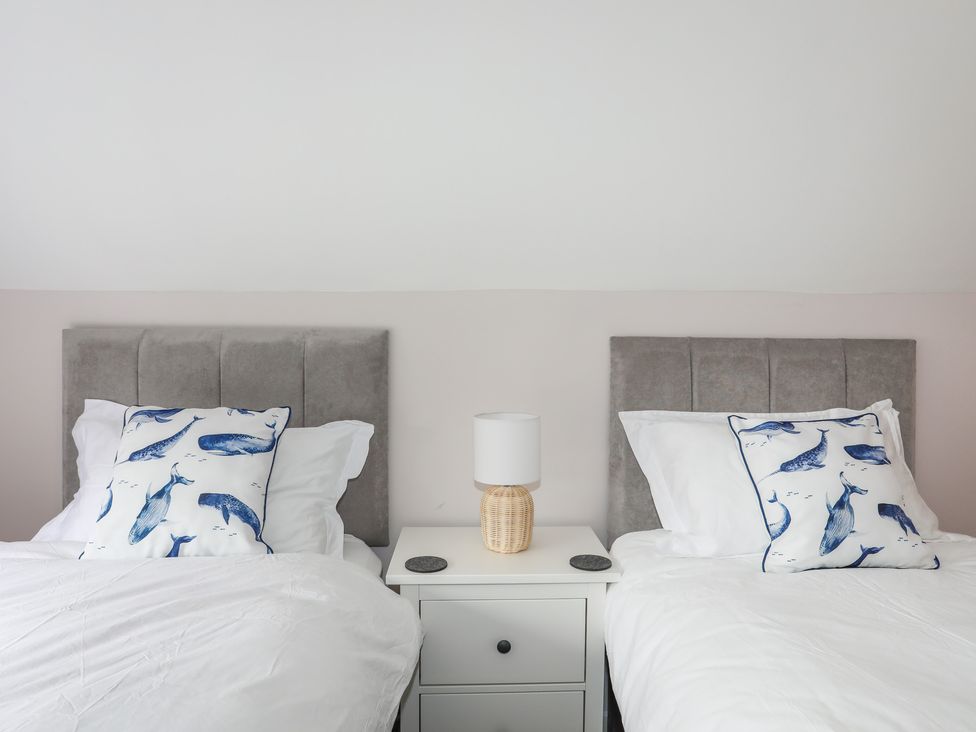 A bedroom with two single beds a nightstand and a lamp at Swn Y Mor in Benllech
