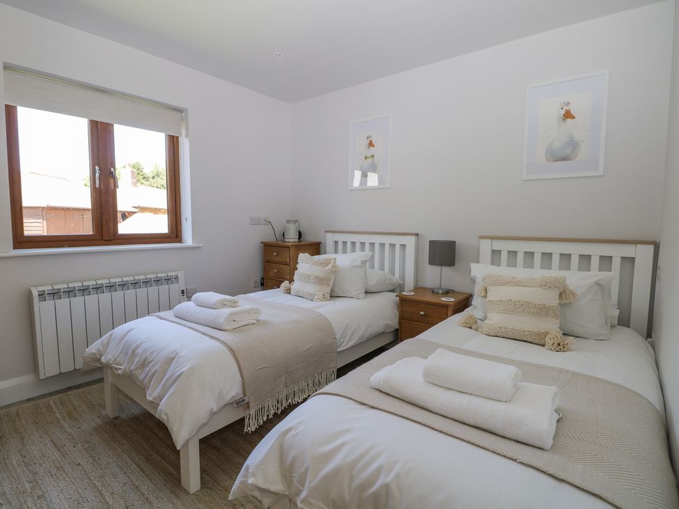 A bedroom with two single beds and wooden furniture at Robins Nest in Titchfield Common