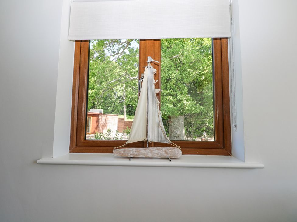 A window with a small decorative sailboat on the windowsill at Robins Nest in Titchfield Common