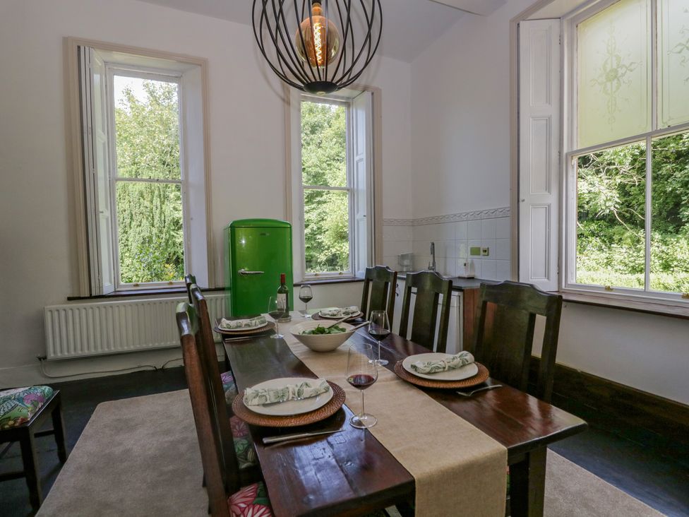 A dining room with a wooden table set for four people and a green refrigerator by the windows at The Residence in Cleator