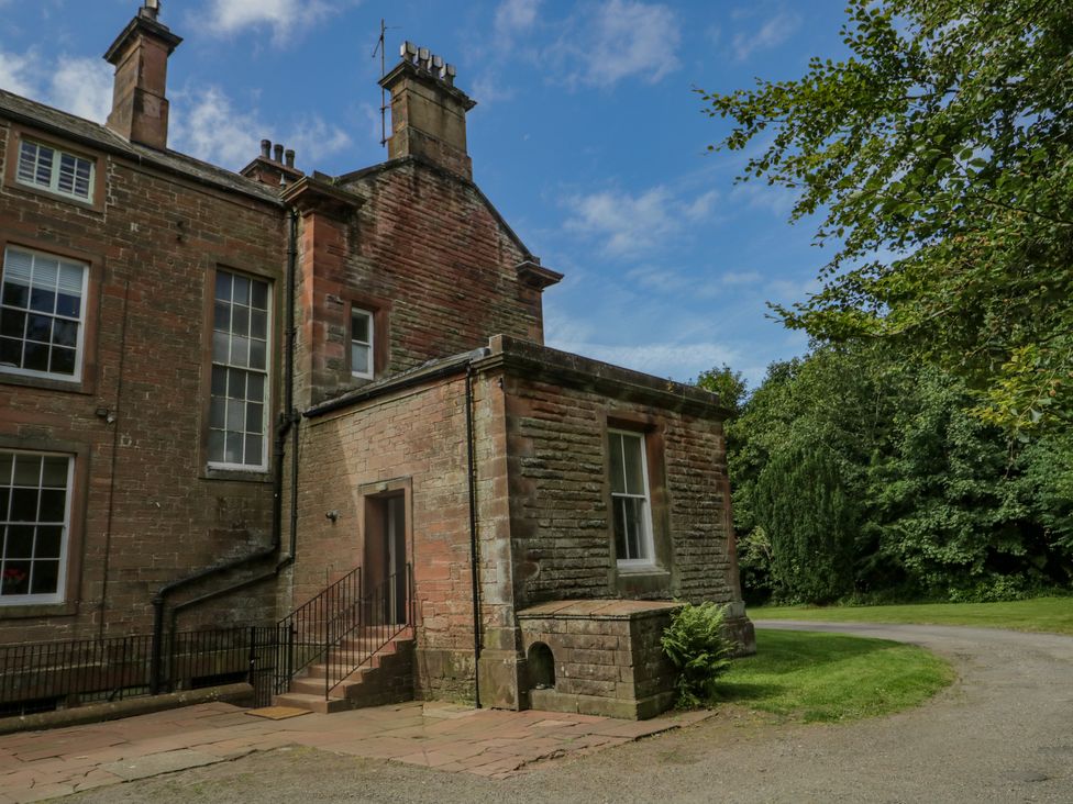 The exterior of a brick building with chimneys and windows surrounded by grass and trees at The Residence in Cleator