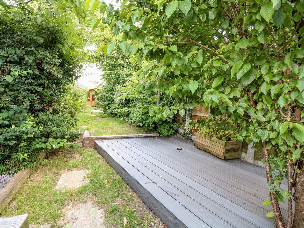 A garden with wooden decking and a wooden shed at Vintner's Cottage in Freethorpe near Reedham