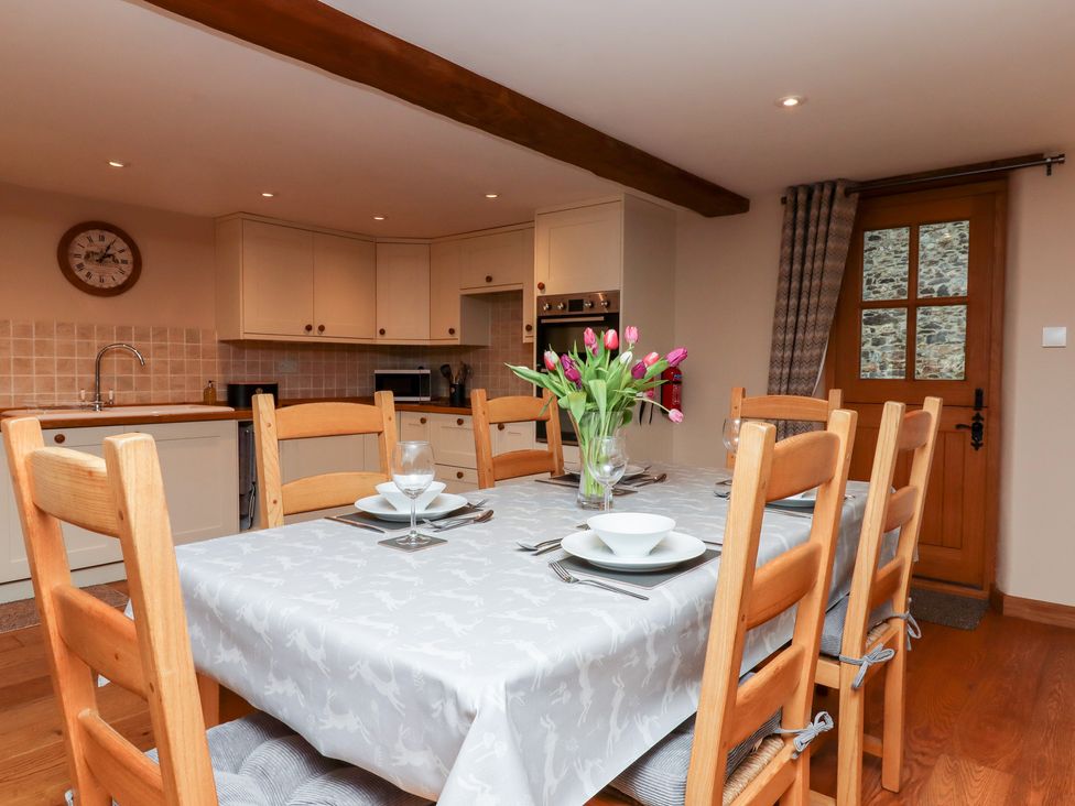 A kitchen with a dining table set with dishes and a vase of flowers at Little Orchard in Ashburton Down near Ashburton
