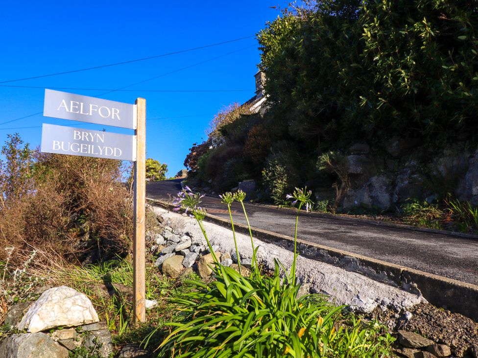 A road with a signpost and plants along the side at Aelfor in Harlech