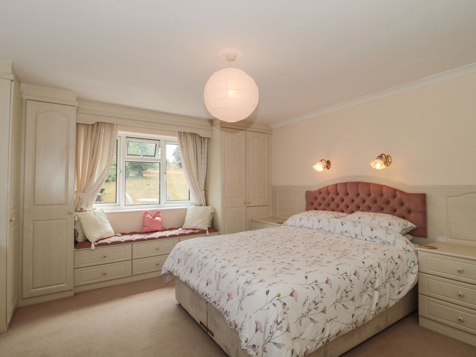A bedroom with a bed a window seat with cushions and built in wardrobes at Rhode Acres in Fifehead Neville near Hazelbury Bryan
