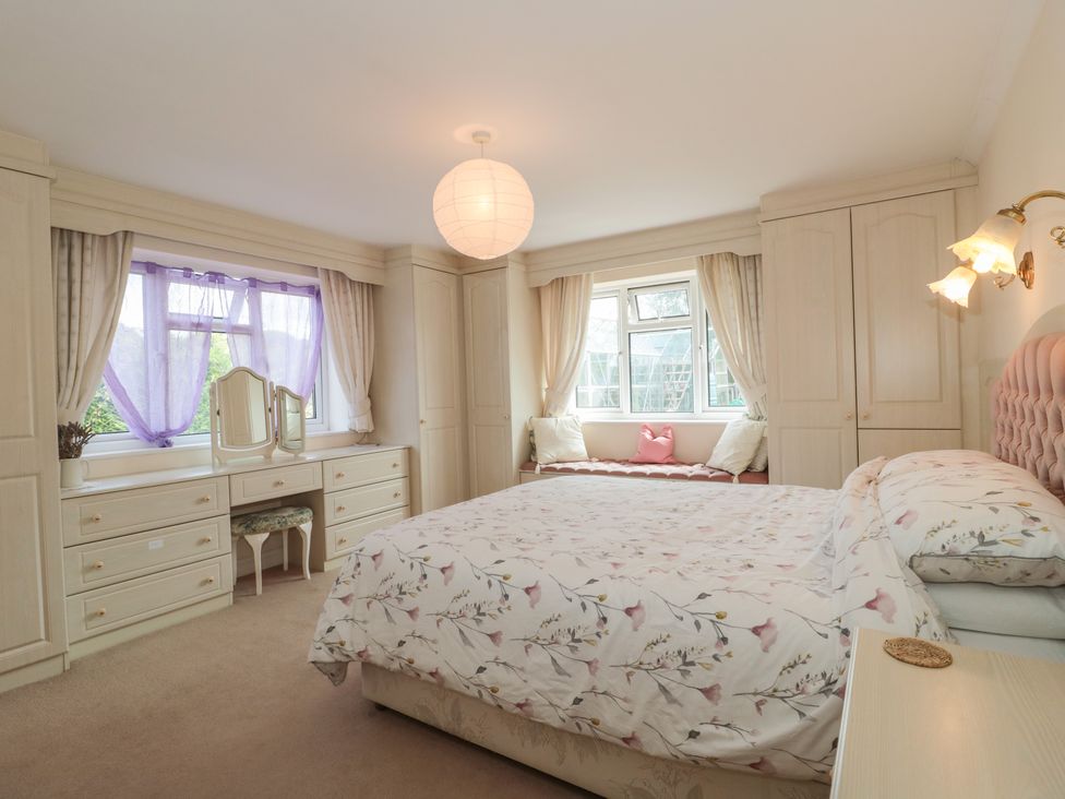A bedroom with a bed a vanity table cabinets and a window seat at Rhode Acres in Fifehead Neville near Hazelbury Bryan