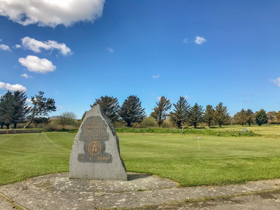 A golf course with a stone monument in the foreground and trees in the background at Hen Felin in Llangybi near Pwllheli