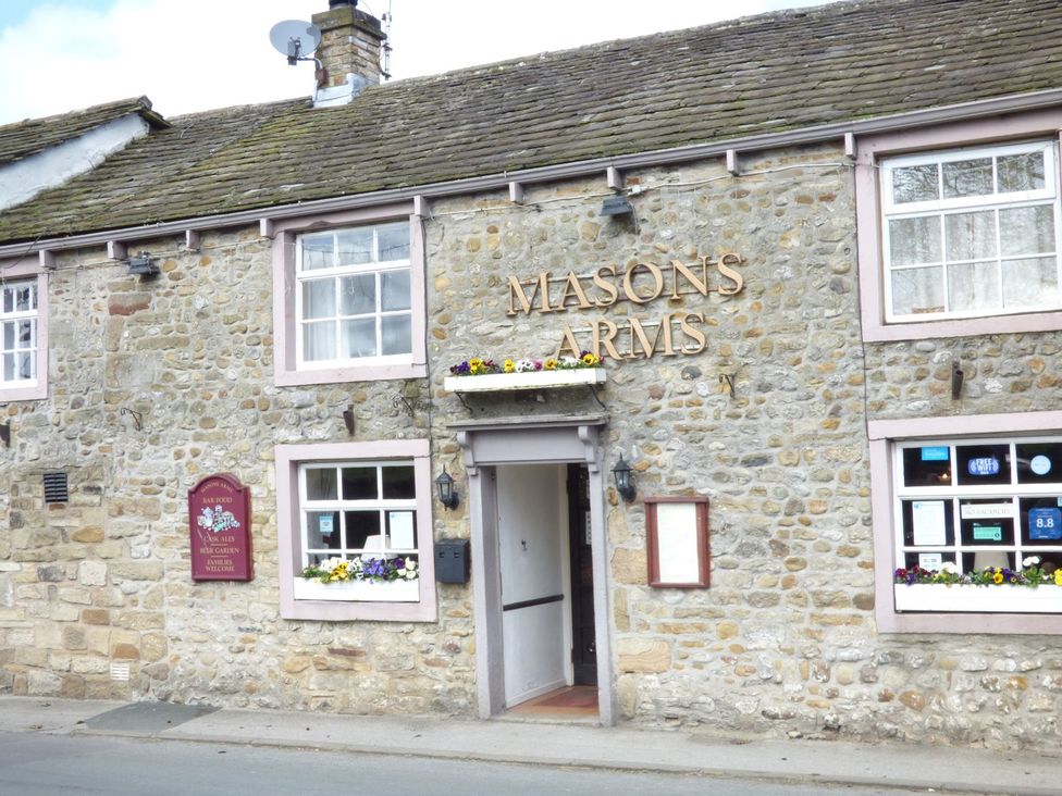 Stone building with windows and flowers on sills and a sign reading Masons Arms