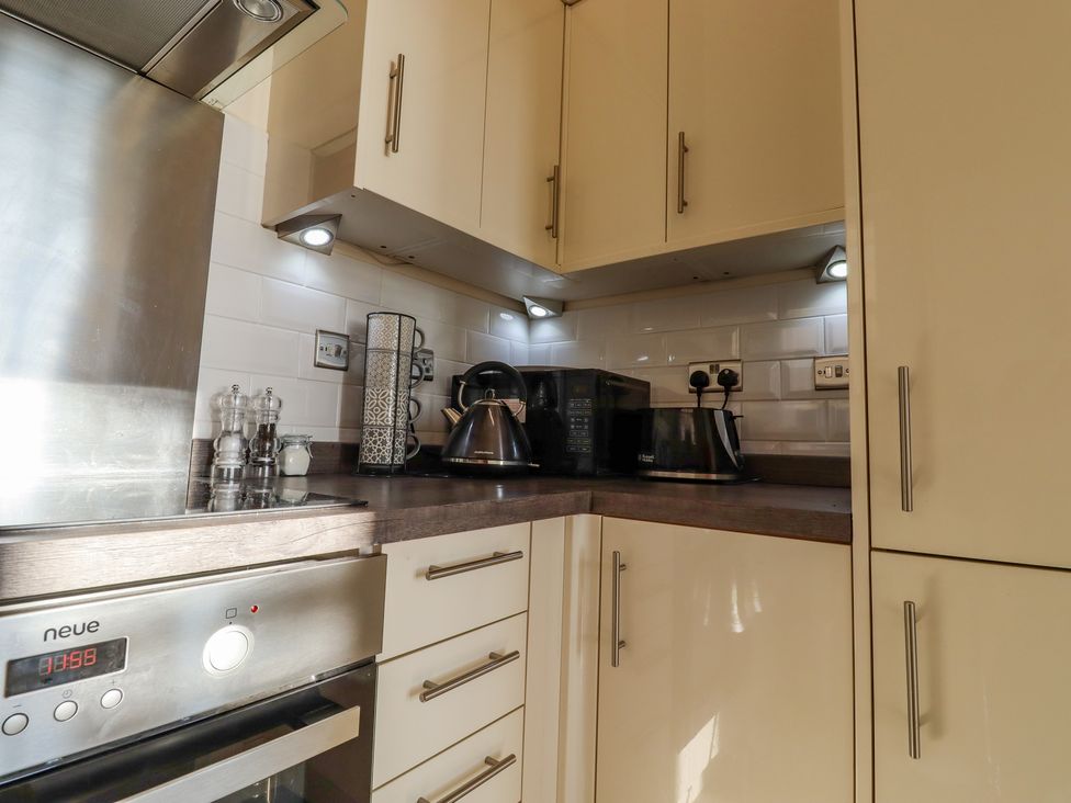 A kitchen corner with a microwave toaster and electric kettle on the counter and built in oven at The Old Spy Headquarters in Folkestone