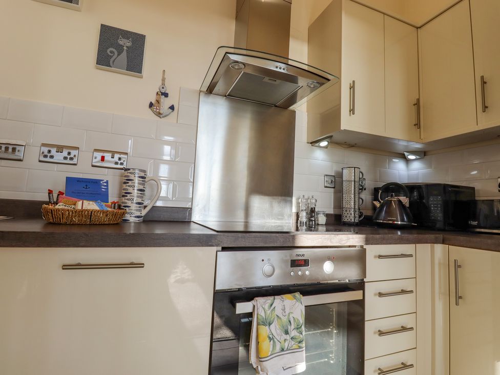 A kitchen with a stainless steel oven and hob a kettle microwave white cabinets and a countertop basket at The Old Spy Headquarters in Folkestone