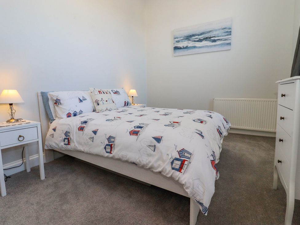 A bedroom with a bed and patterned bedding two bedside tables with lamps a chest of drawers and a painting on the wall at The Old Spy Headquarters in Folkestone