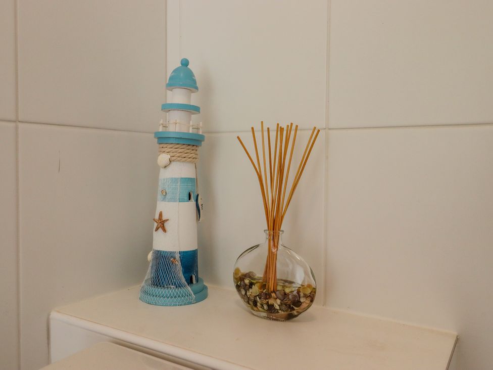 A decorative lighthouse and a glass vase with reed diffuser sticks on a tiled surface at The Old Spy Headquarters in Folkestone