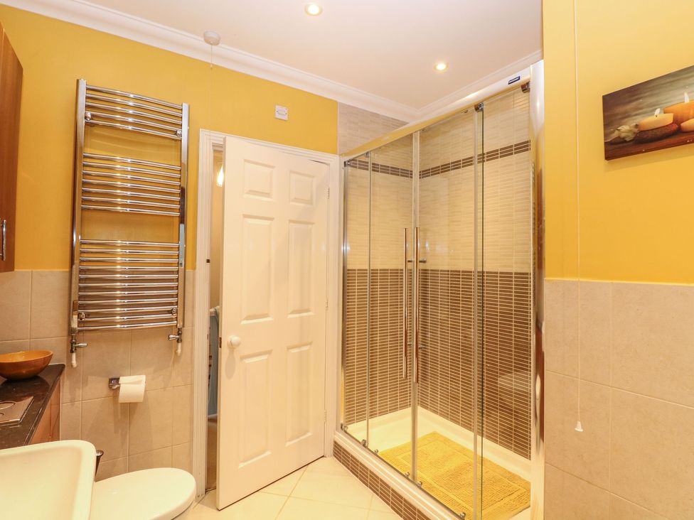 A bathroom with a shower enclosure a heated towel rail a toilet and a white door at Brundall House in Brundall