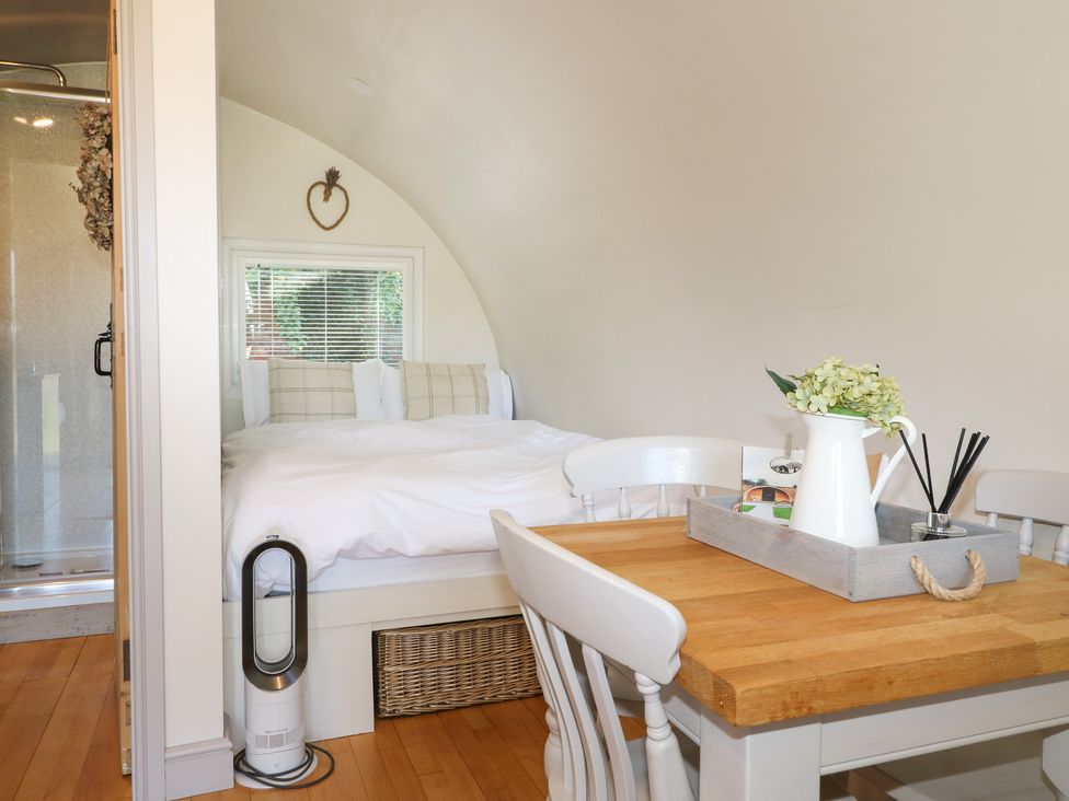 A bedroom with a bed next to a window and a wooden table with chairs and a tray with a flower vase at Elm in Rocester