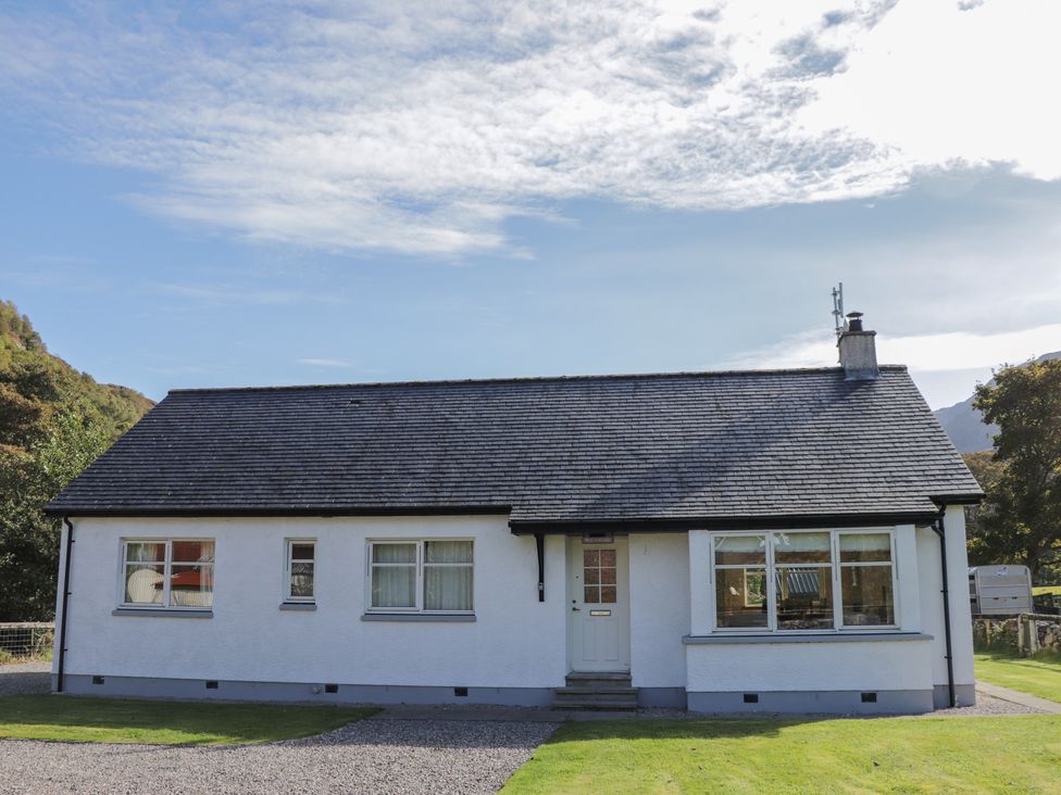 A single story house with white walls and a grey roof with windows and a white door at Tigh na Drochit in Eilanreach near Glenelg