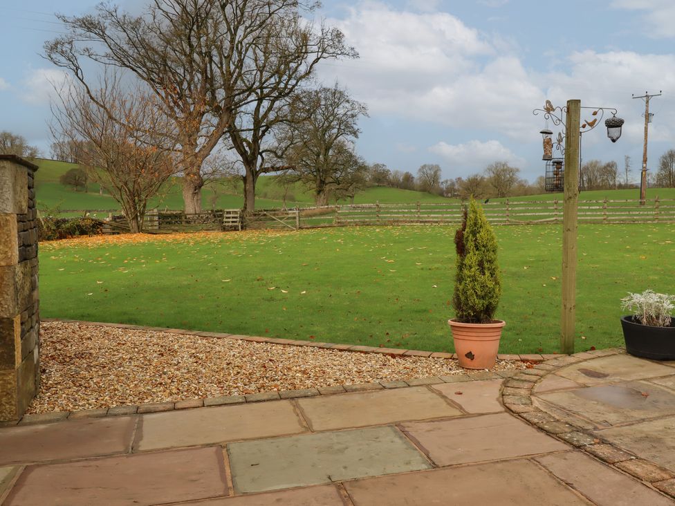 A garden with a stone patio potted plants and bird feeders near a grassy field at Ash Cottage in Bell Busk near Gargrave