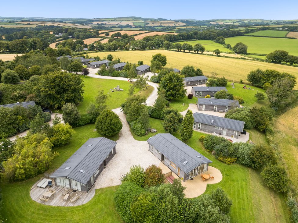 A cluster of small houses with pathways and trees surrounded by fields at 11 Meadow Retreat in Dobwalls