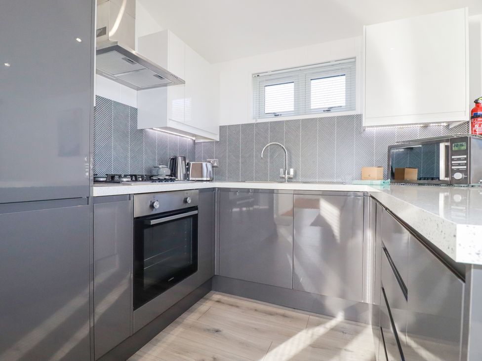 A kitchen with grey cabinets white countertops a stainless steel oven and microwave at 11 Meadow Retreat Dobwalls