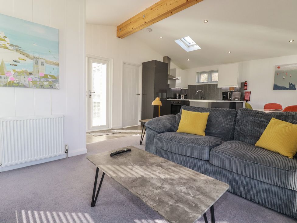 A living room with a grey sofa and yellow cushions and a kitchen area in the background at 11 Meadow Retreat Dobwalls