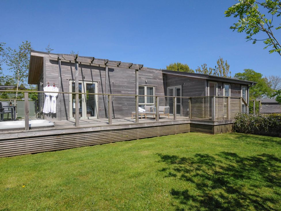 An outdoor view of a wooden house with a deck chairs and robes hanging on the wall at 11 Meadow Retreat in Dobwalls