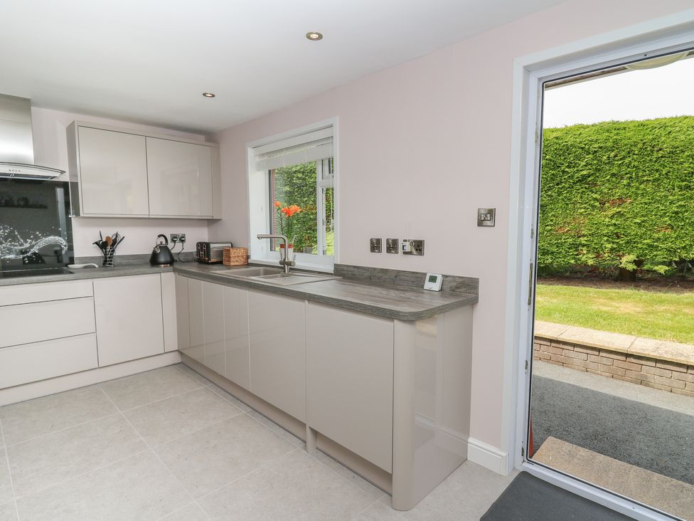 A kitchen with cabinets a sink and a door leading to a garden at Erwlon in Rhydyfelin near Aberystwyth