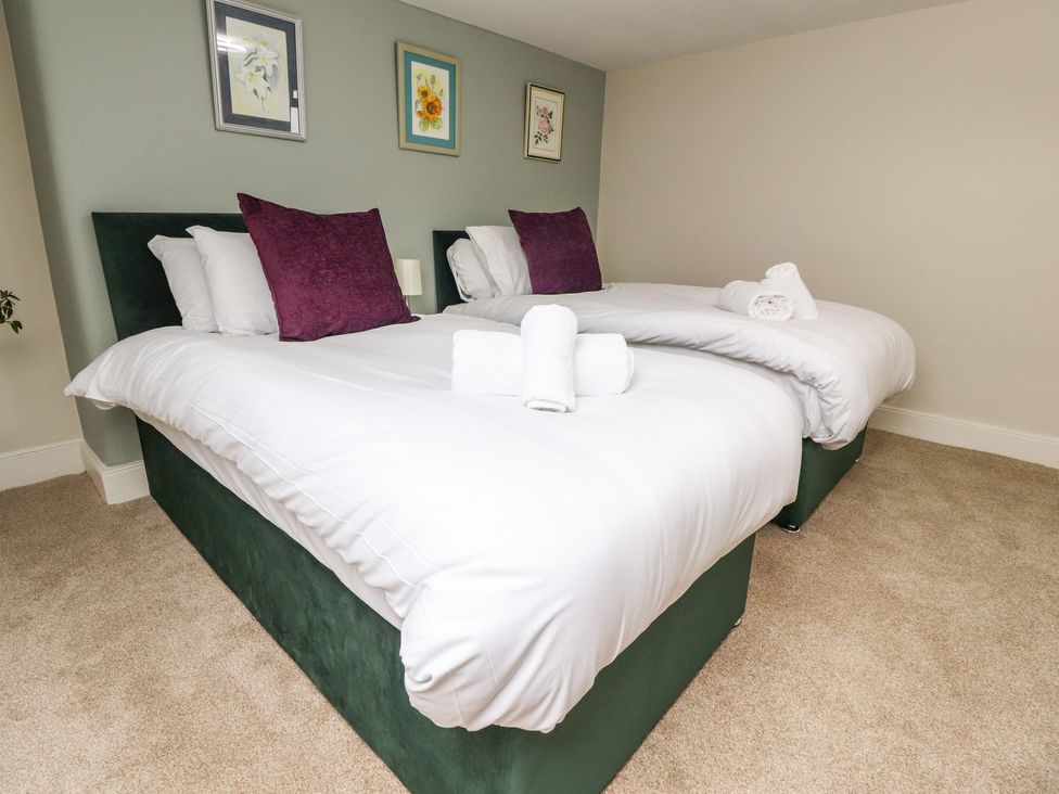 A bedroom with two single beds with white bedding and purple pillows at Mountain View in Hest Bank near Slyne
