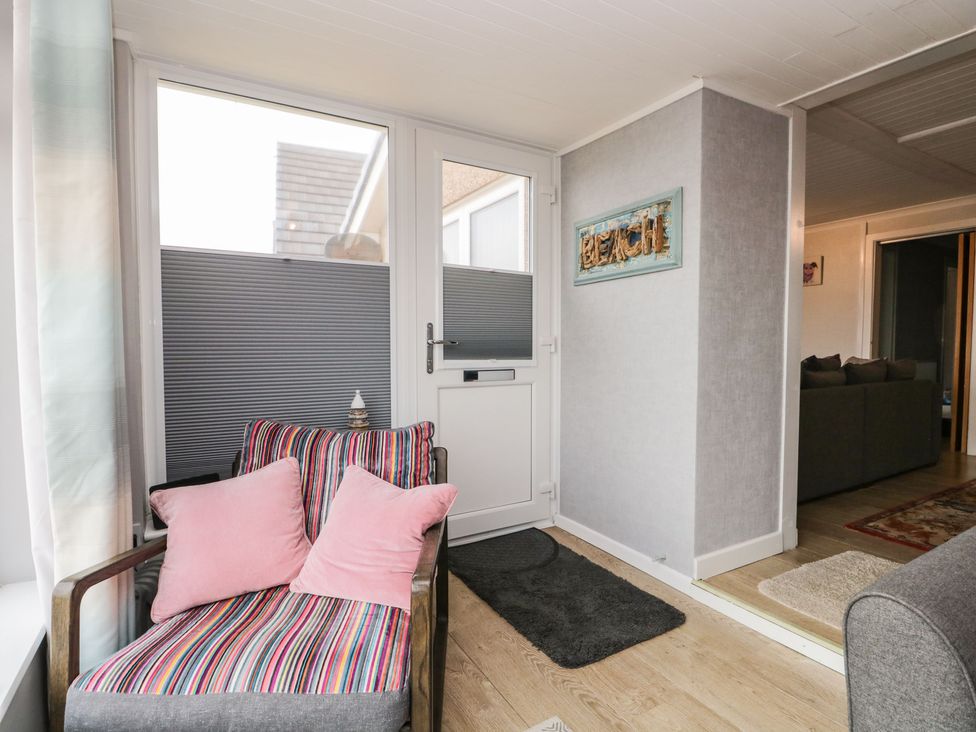 A corner with a striped armchair with pink cushions near a white door and a grey rug at The Chalet in Coulderton near Egremont Cumbria