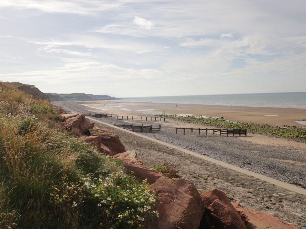 A beach with rocky cliffs grass and flowers in the foreground and the sea visible at The Chalet in Coulderton near Egremont Cumbria