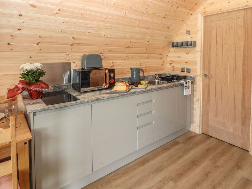 A kitchen with wooden walls a countertop microwave toaster kettle food and a wooden door at Holly in Ulverston