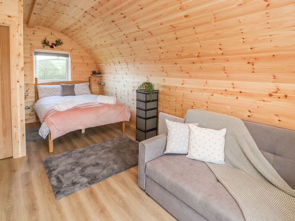 A wooden bedroom with a bed sofa rug and storage drawers at Holly in Ulverston