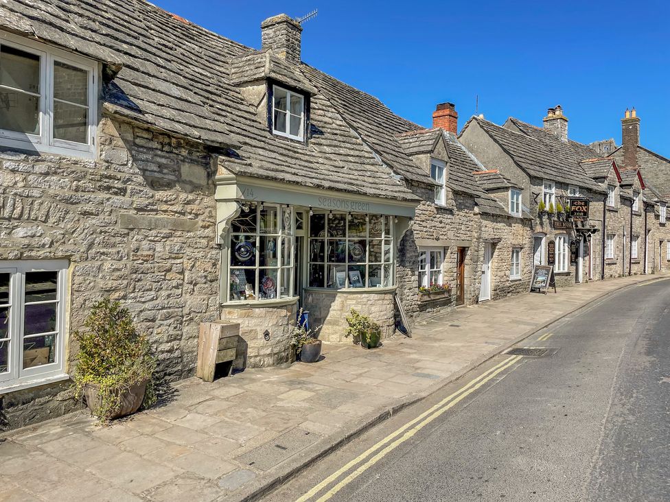 A street with stone buildings including a shop and a pub along a curved road at Lodge 6 in Corfe Castle