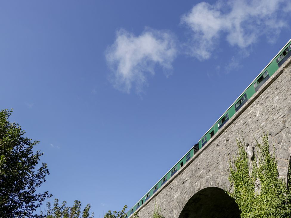 A green train on a stone railway bridge with blue sky and clouds in the background at Lodge 6 in Corfe Castle