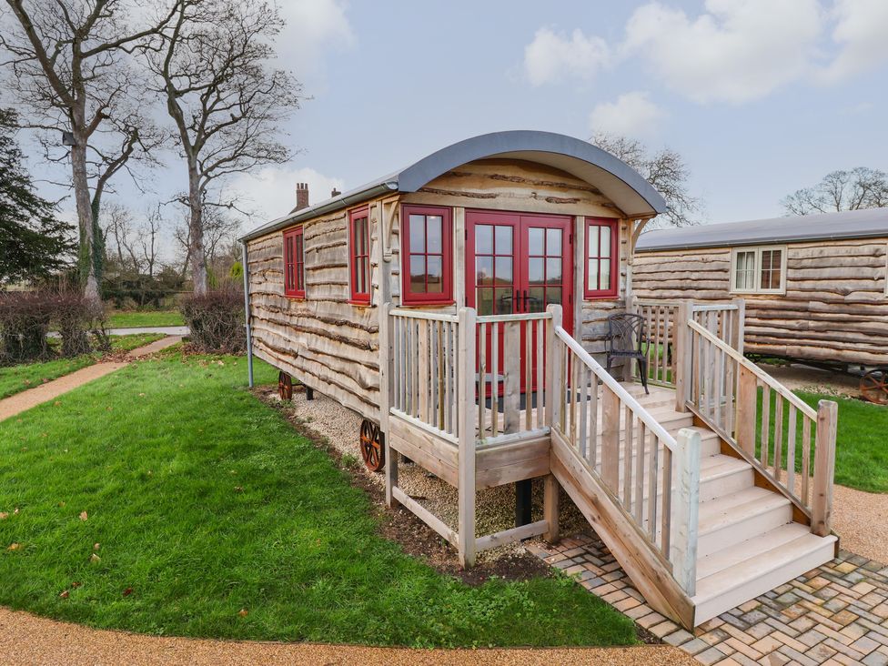 A wooden hut with red framed windows and doors with steps leading to the entrance on a grassy area at The White Princess in Bolton Percy near Tadcaster